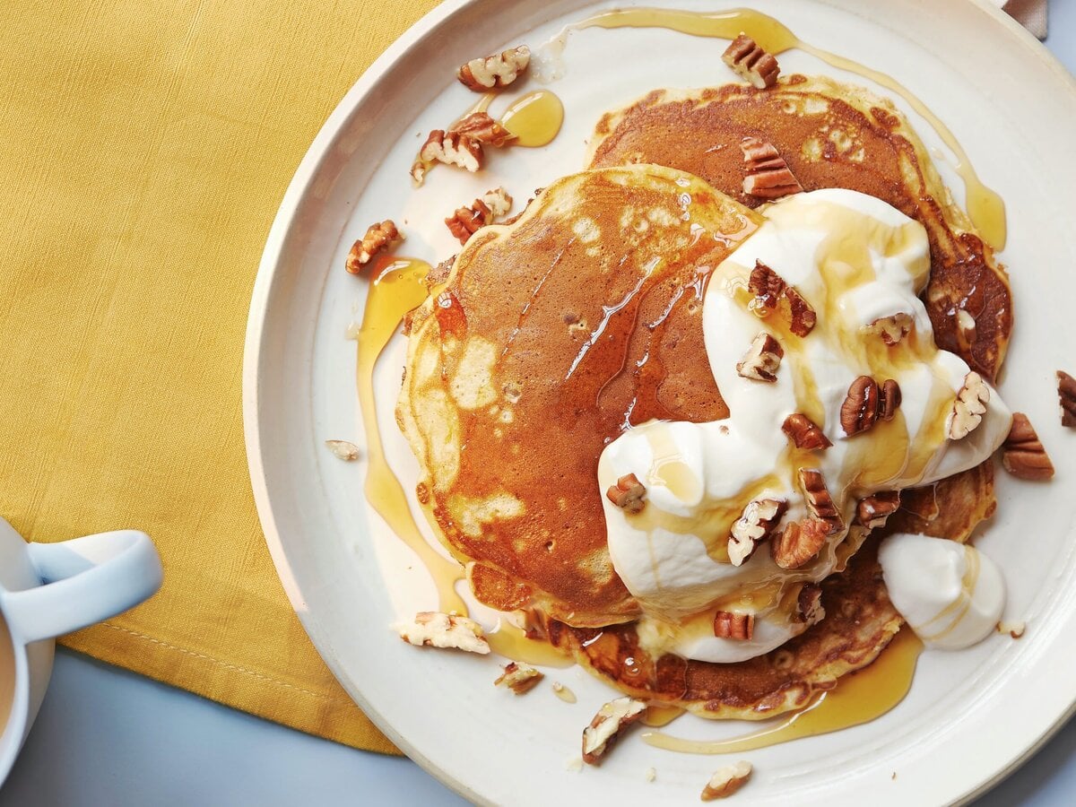 Carrot-cakepancakes, geserveerd met honing, yoghurt-roomkaas en walnoten