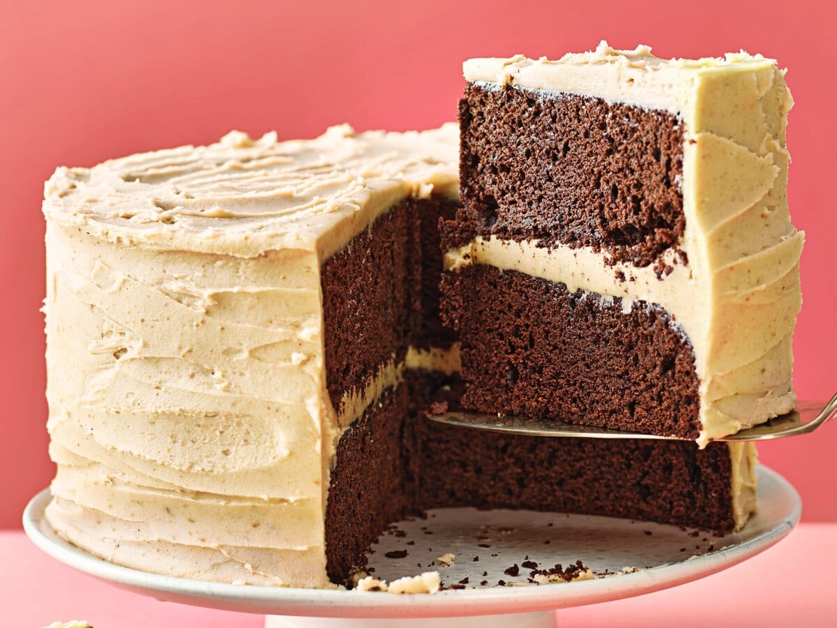 Tweelaagse chocoladetaart met beurre-noisette-frosting op een taartplateau met een stuk eruit