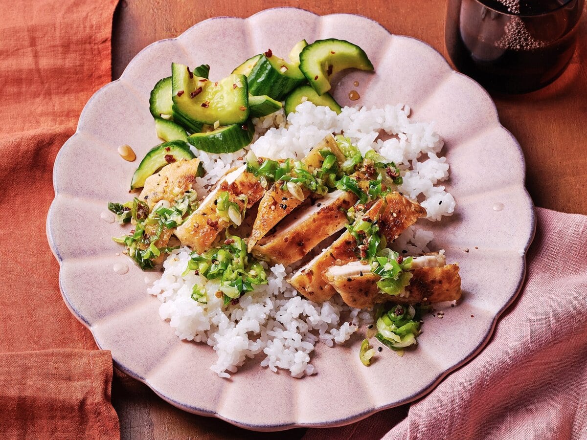 Witte rijst met crispy kip met lente-ui-gemberolie, geserveerd met komkommer