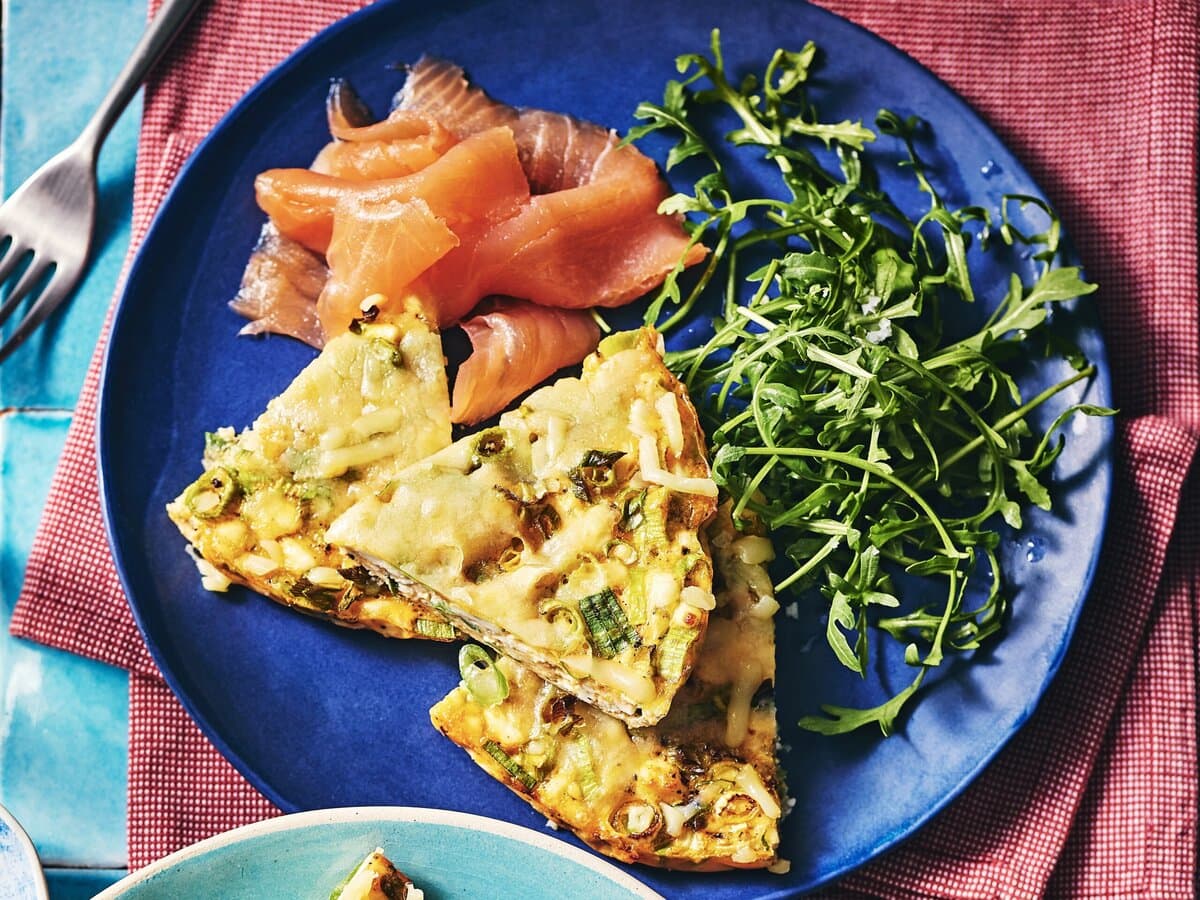 Fetafrittata met lente-ui en cheddar, geserveerd met rucola en gerookte zalm
