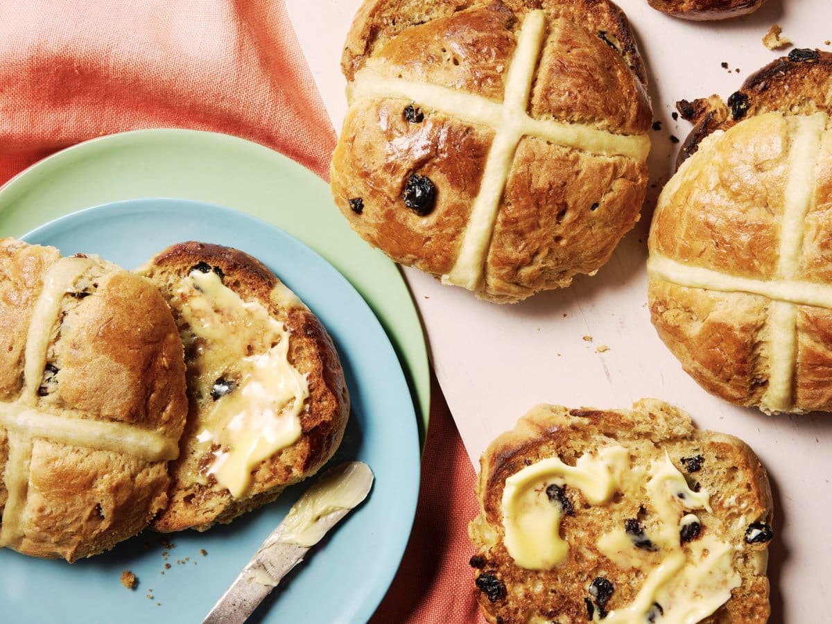 Hot cross buns met kersen en blonde chocolade, doormidden gesneden en besmeerd met boter