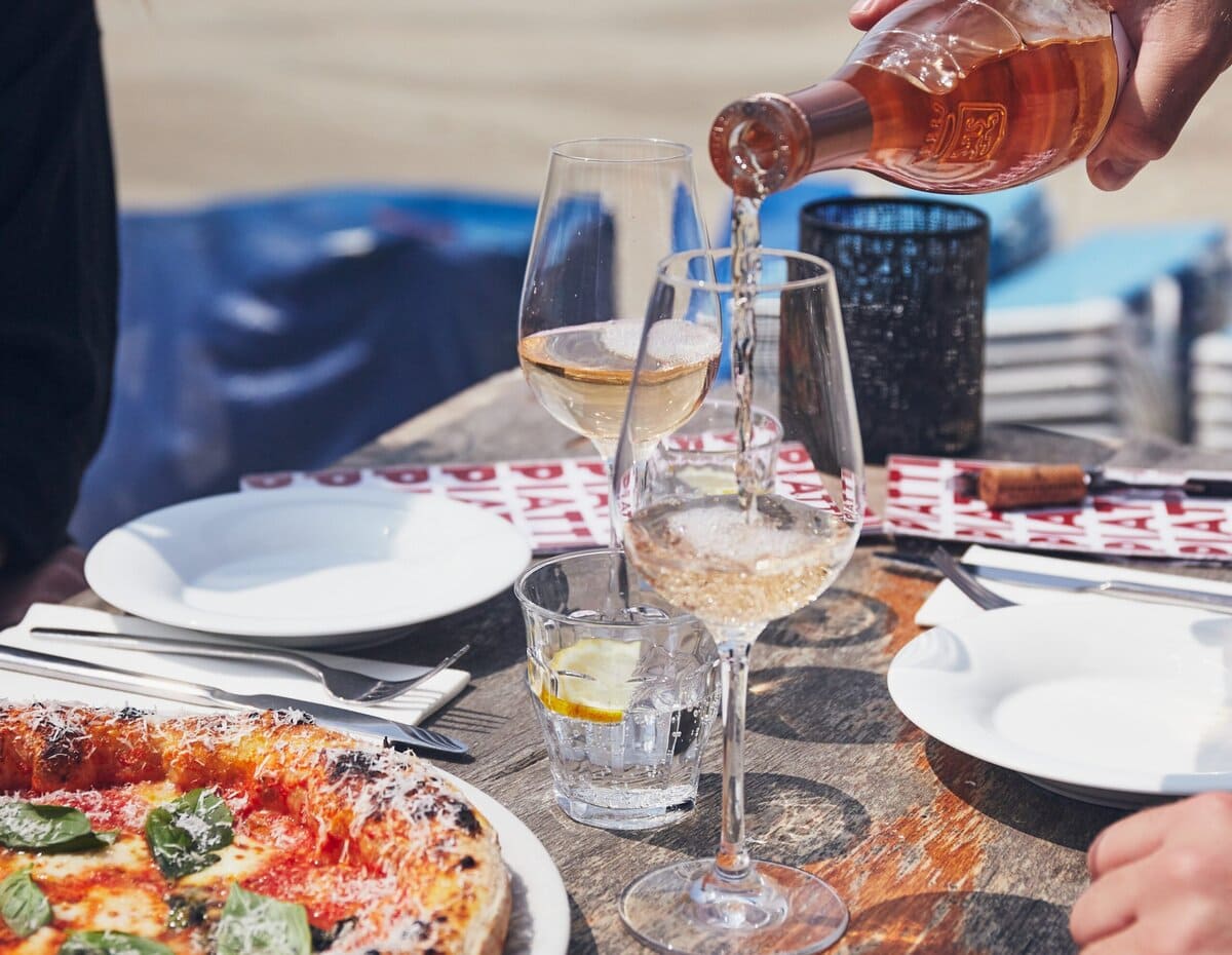 Pizza en wijn op een terras aan het strand
