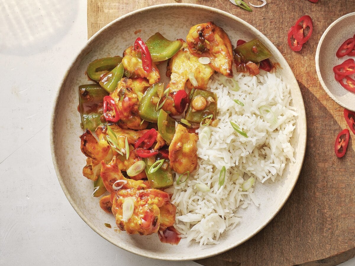 Indiaas-Chinese geroosterde bloemkool, groene paprika, rode peper en lente-ui, geserveerd met rijst