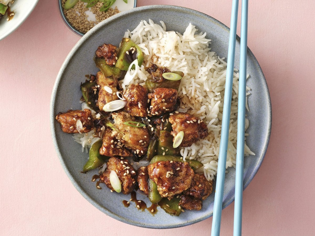 Bakje kung pao met tofu, groene paprika, lente-ui en sesamzaad, geserveerd met witte rijst