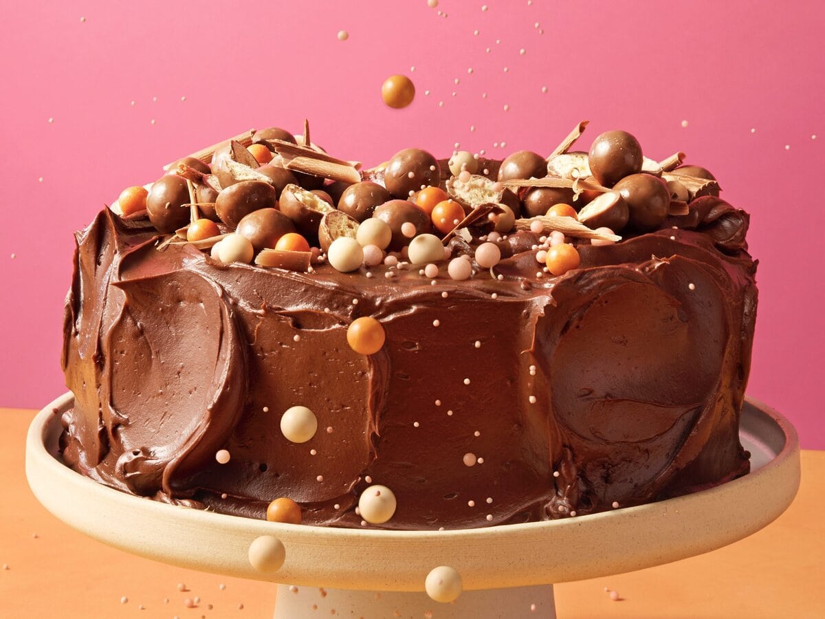 Chocoladetaart met mascarponebotercrème met bovenop maltesers, sprinkels en chocoladeschaafsel op een taartplateau