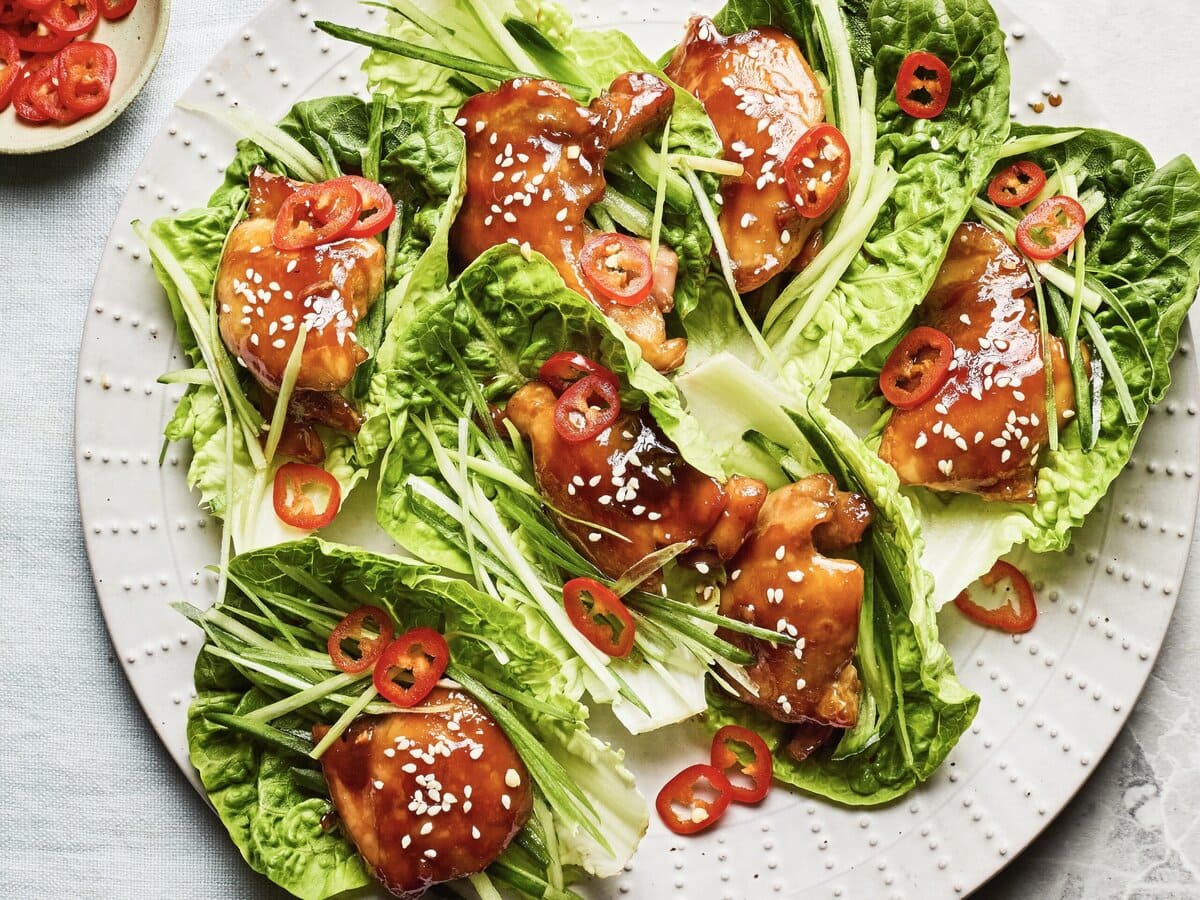 Romainesla met sticky honing-hoisinkip, komkommer in dunne reepjes, sesamzaadjes en rode peper