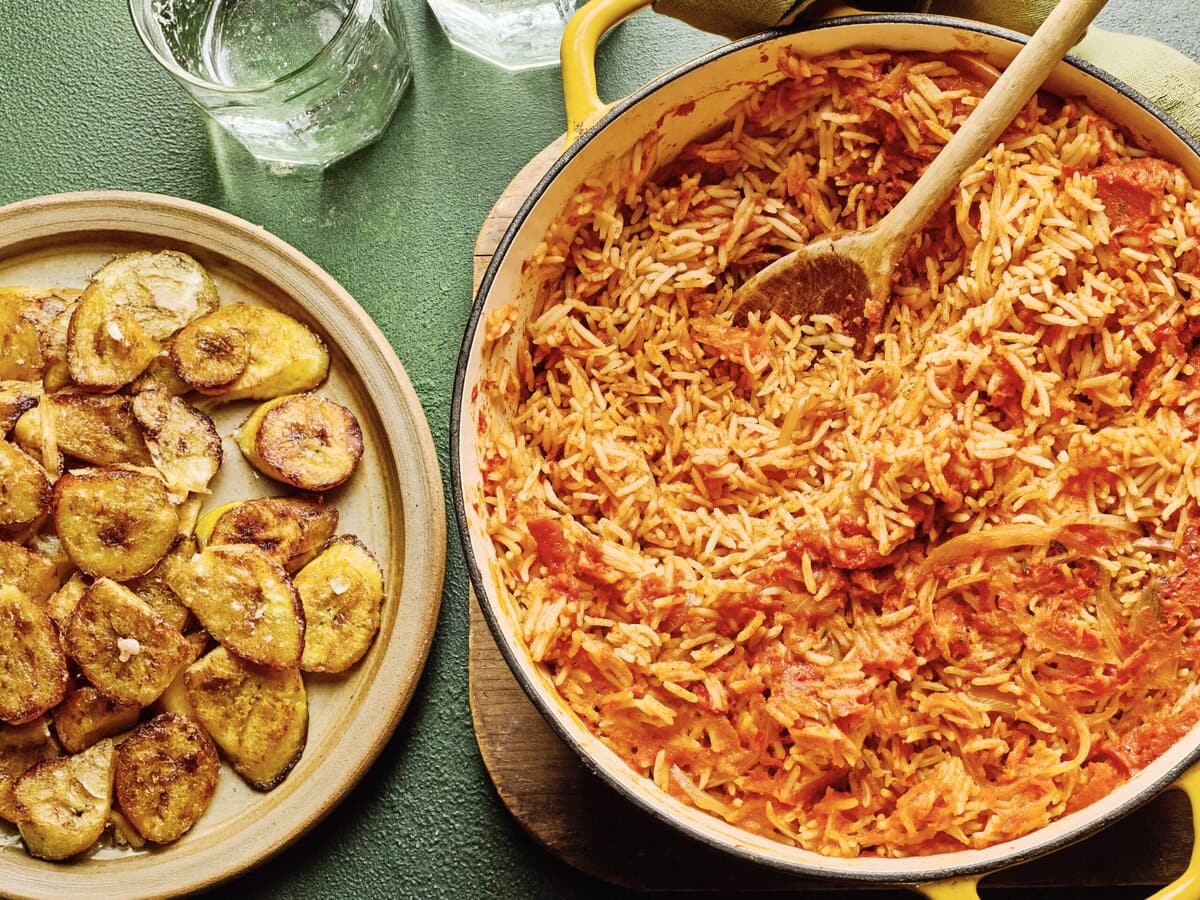 Smoky jollofrijst in een pan, met daarnaast een bord gebakken banaan