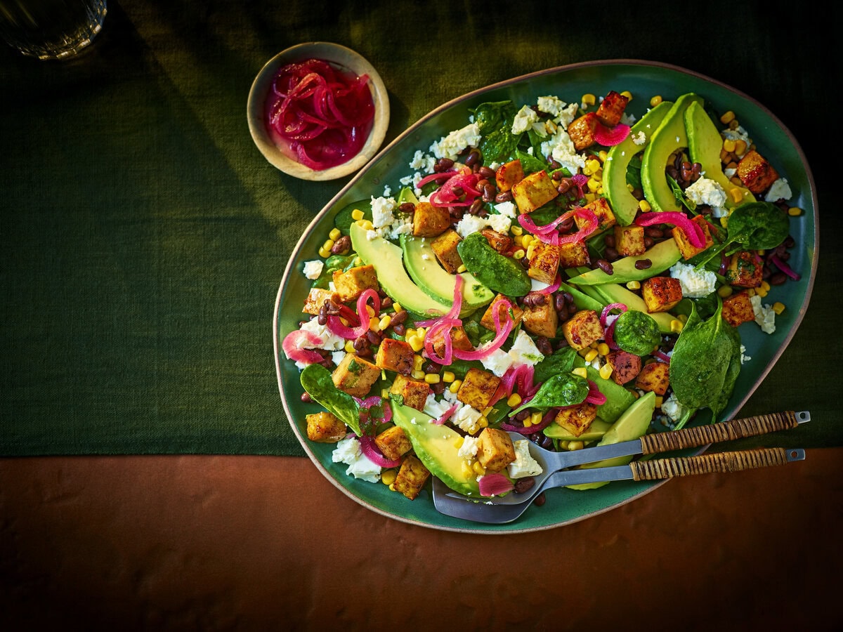 Salade met avocado, ingelegde rode ui, maïs, tofu, spinazie, feta en zwarte bonen