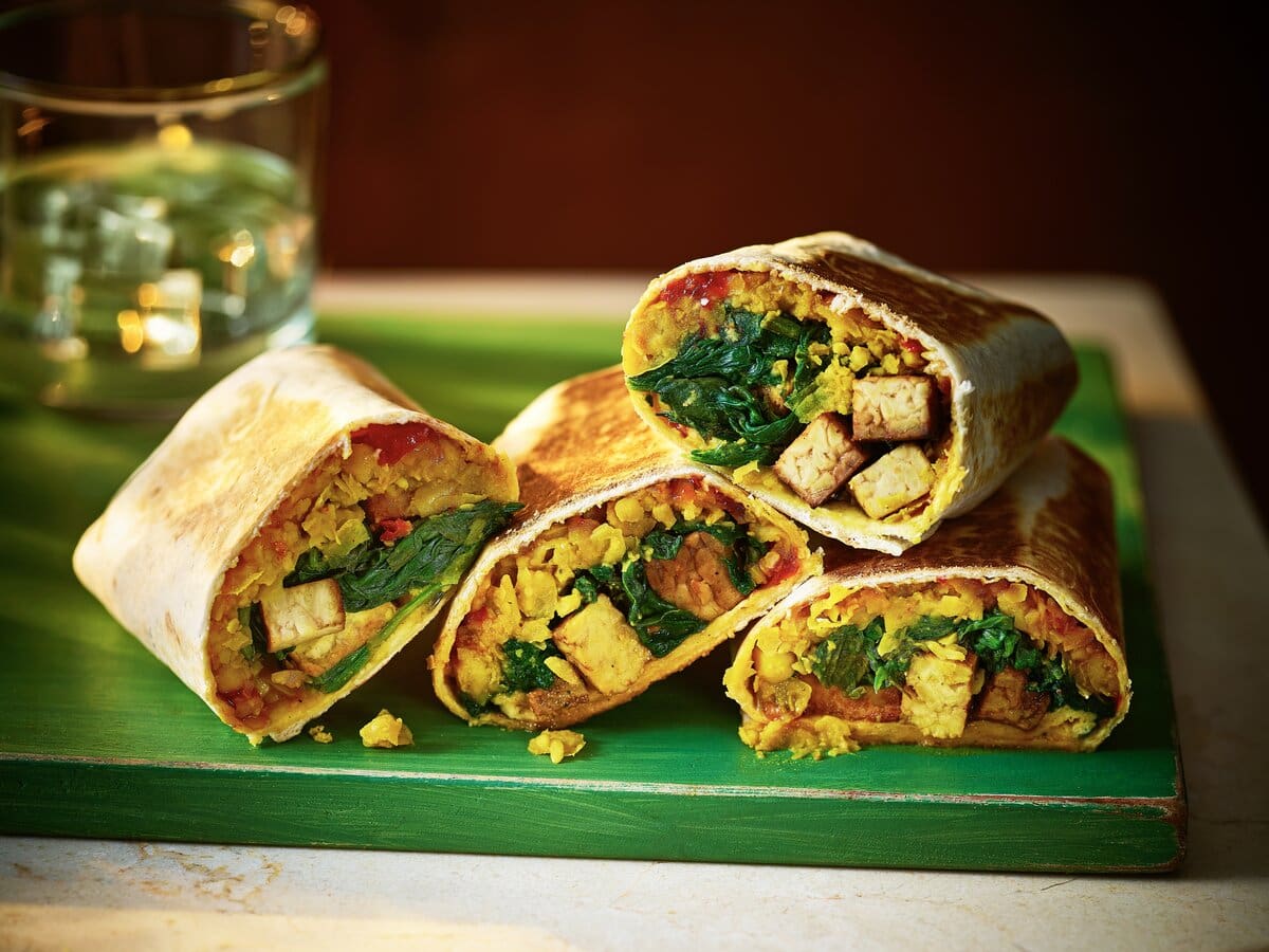 Twee doorgesneden wraps met tempeh, kikkererwtendahl en spinazie