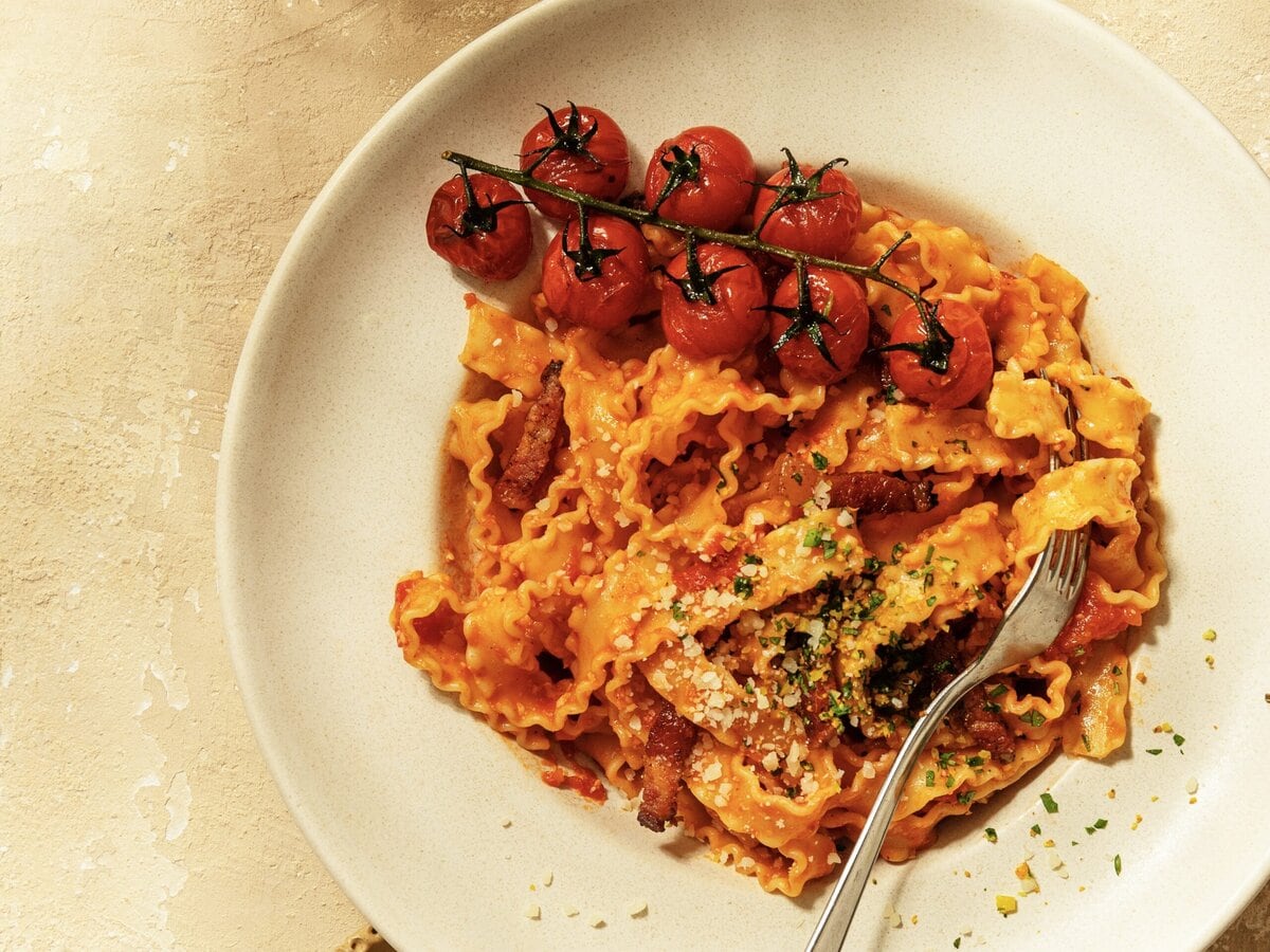 Mafaldine amatriciana met rode saus, guanciale, gremolata en een geroosterde tros cherrytomaten