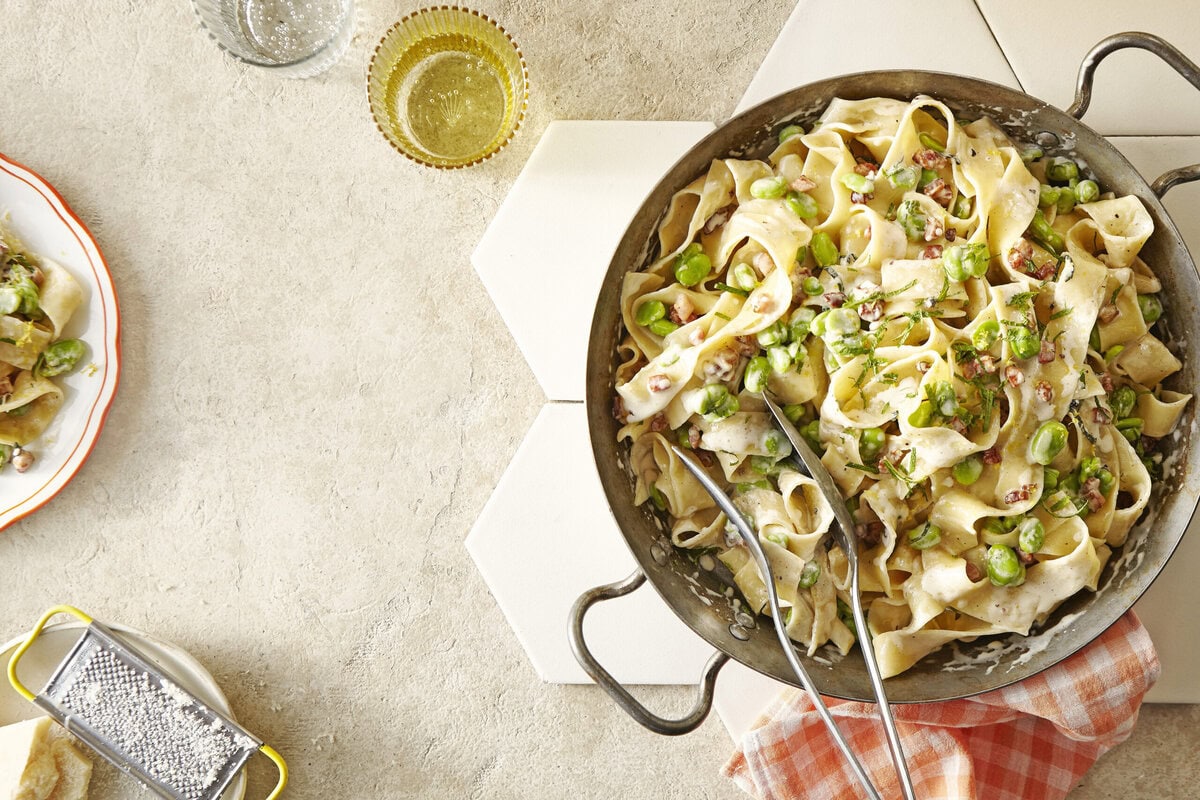 Romige pasta met tuinbonen, bacon en munt in een pan