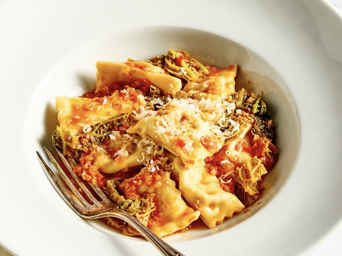 Agnolotti, gevuld met rund en geserveerd met koolsaus en bestrooid met grana padano