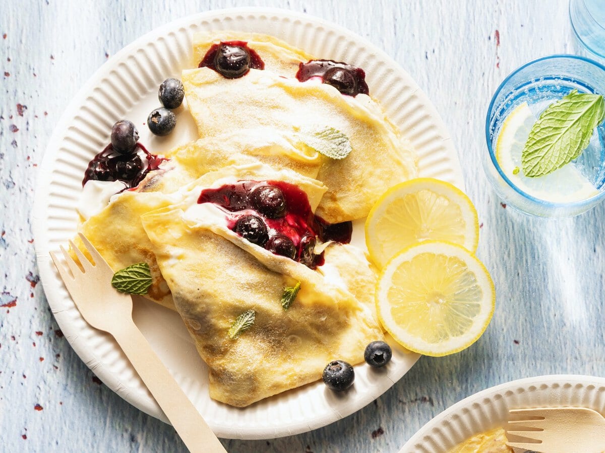 Crêpes met citroenricotta en bosbessencompote, geserveerd met schijfjes citroen