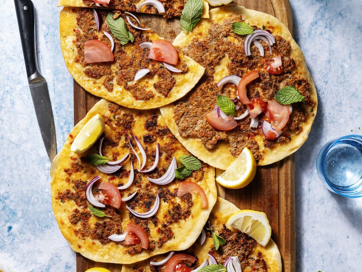 4 lahmacun met rode ui, tomaat, munt en citroenpartjes
