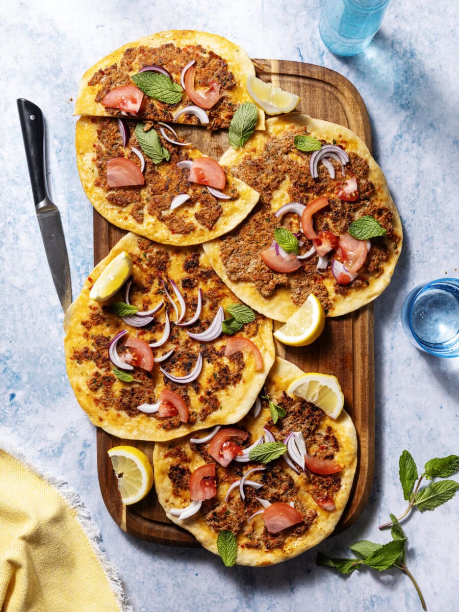 4 lahmacun met rode ui, tomaat, munt en citroenpartjes