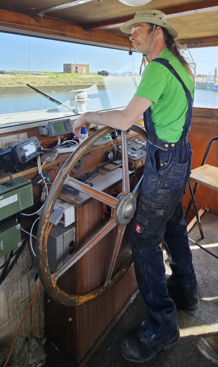 Jan aan het roer van zijn schip op de Waddenzee