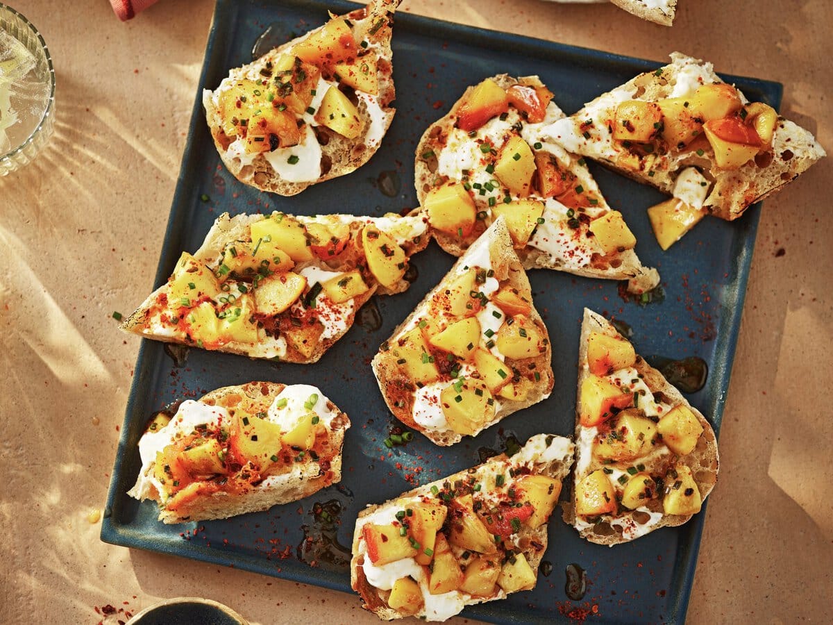 Bruschetta met een laagje stracciatella, gegrilde perzik en kruiden