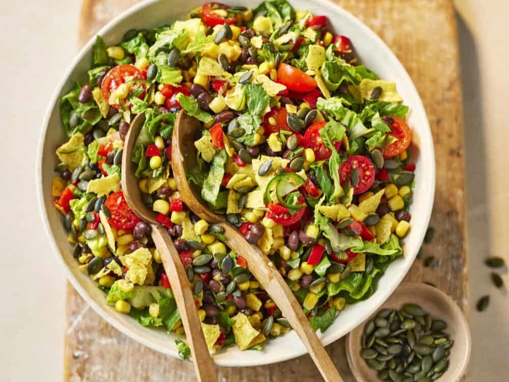 Tacosalade met tomaat en zwarte bonen in een schaal met pompoenpitten