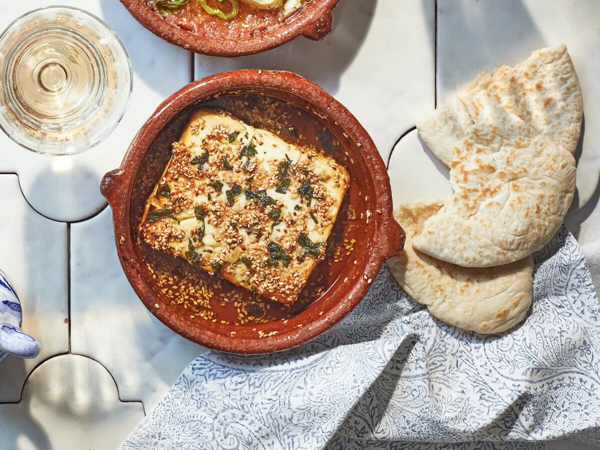 Gebakken feta met sesam en honing in een tapasschaaltje, geserveerd met pitabroodjes