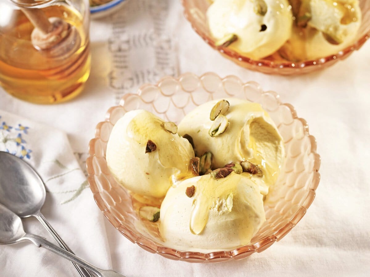 Bakje met 3 bolletjes honing-limoenroomijs, met honing en pistachenootjes erover