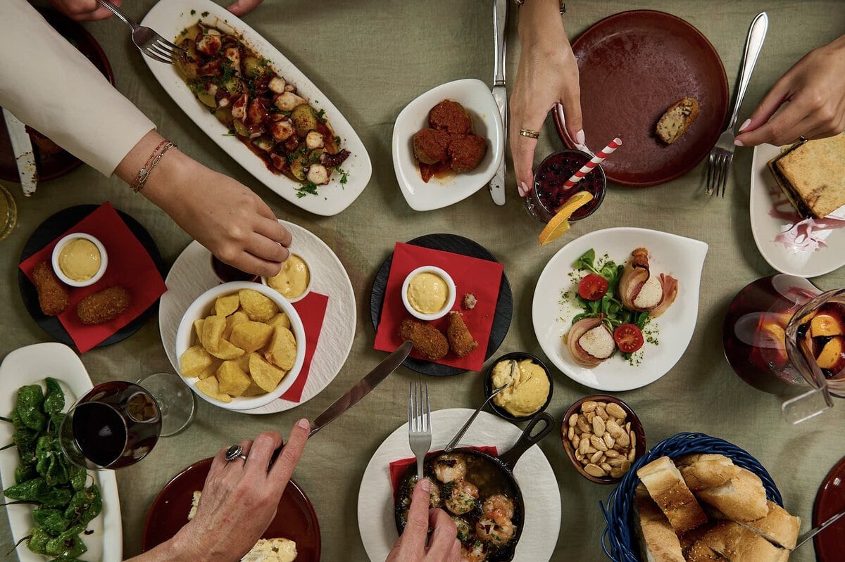 Tafel vol met tapas, zoals patatas bravas, padron pepers, garnalen