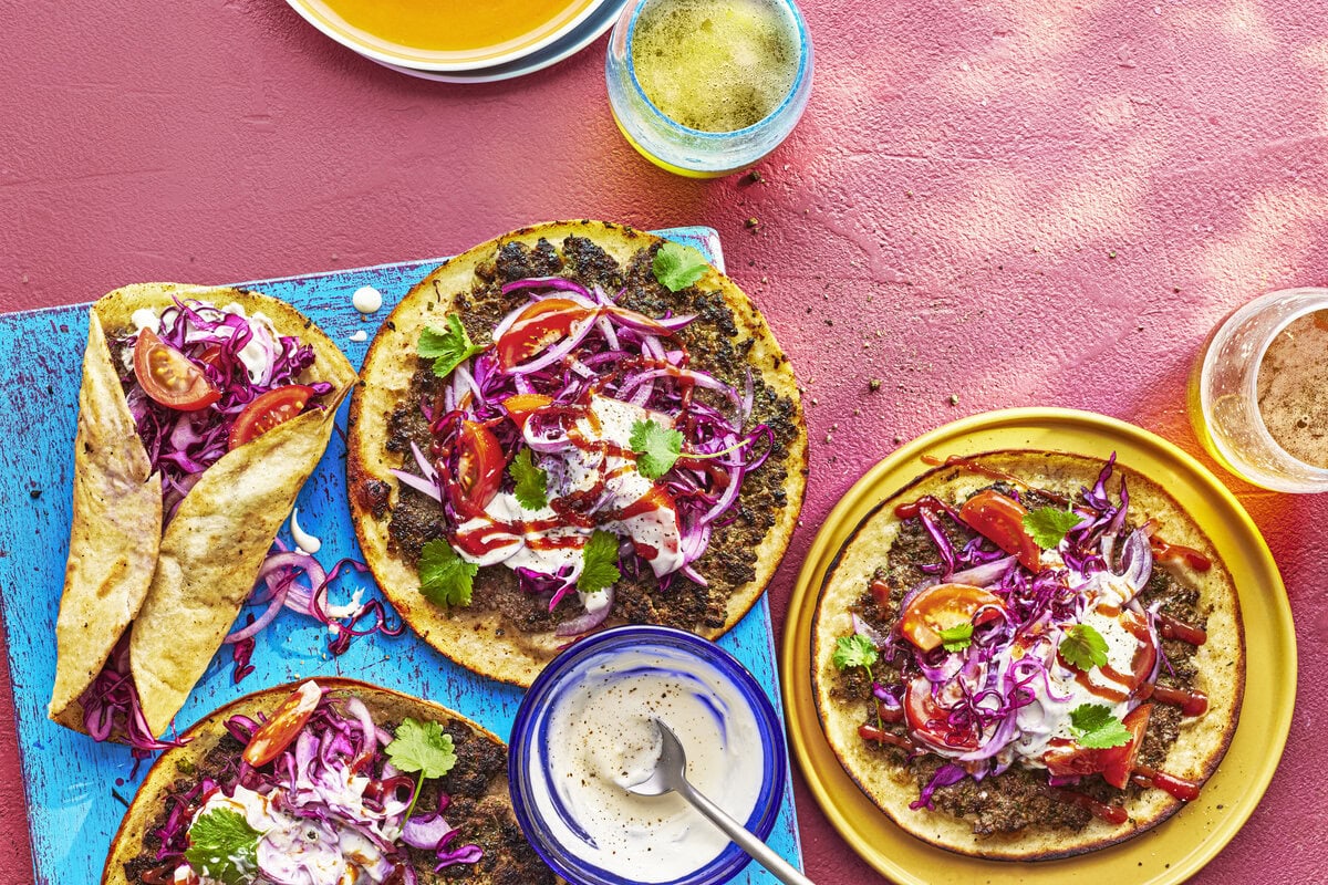 Taco's met smashed-köfte met daarop rode ui, tomaat en knoflooksaus