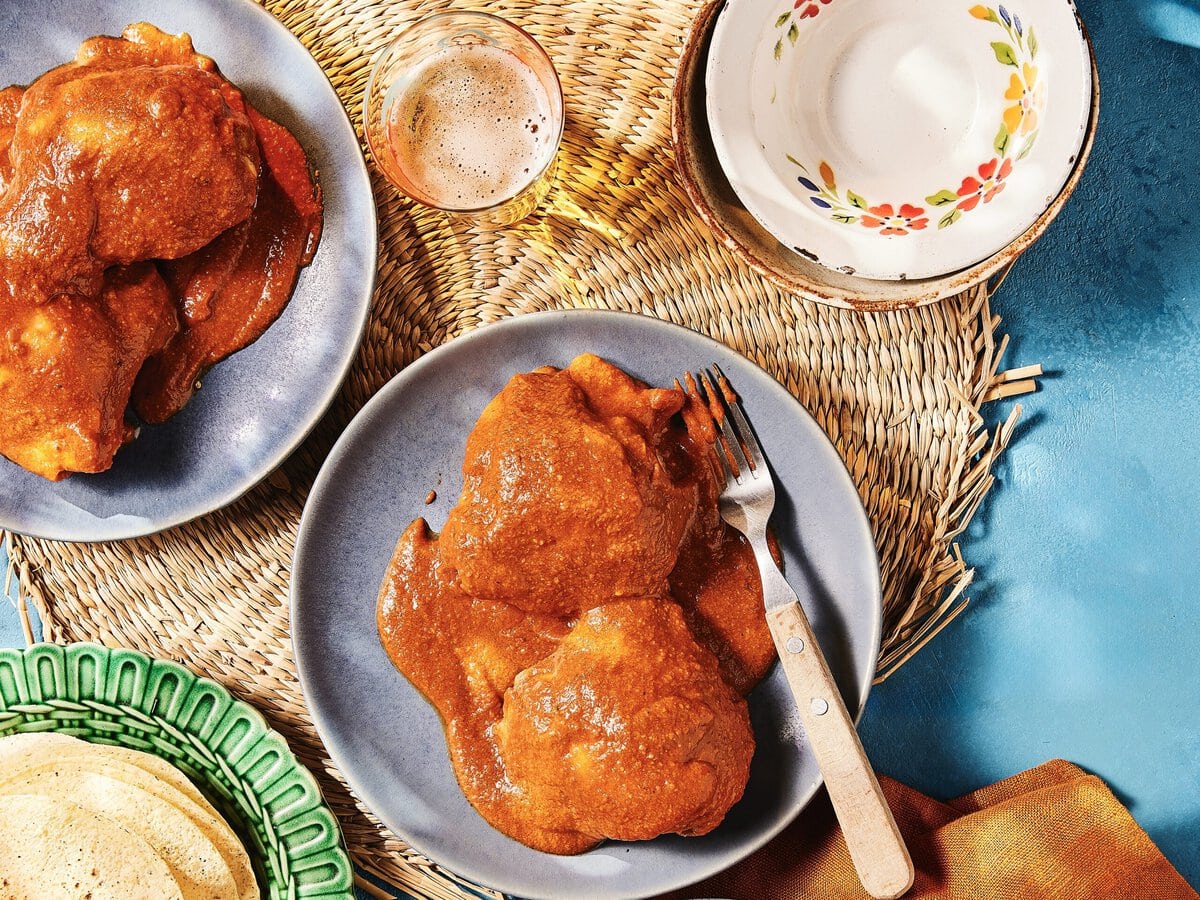 Twee bordjes spicy kip met een rode saus, mole rojo