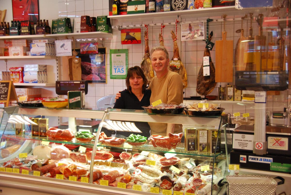 Twee mensen achter een vitrine met vlees in een Spaanse delicatessenwinkel