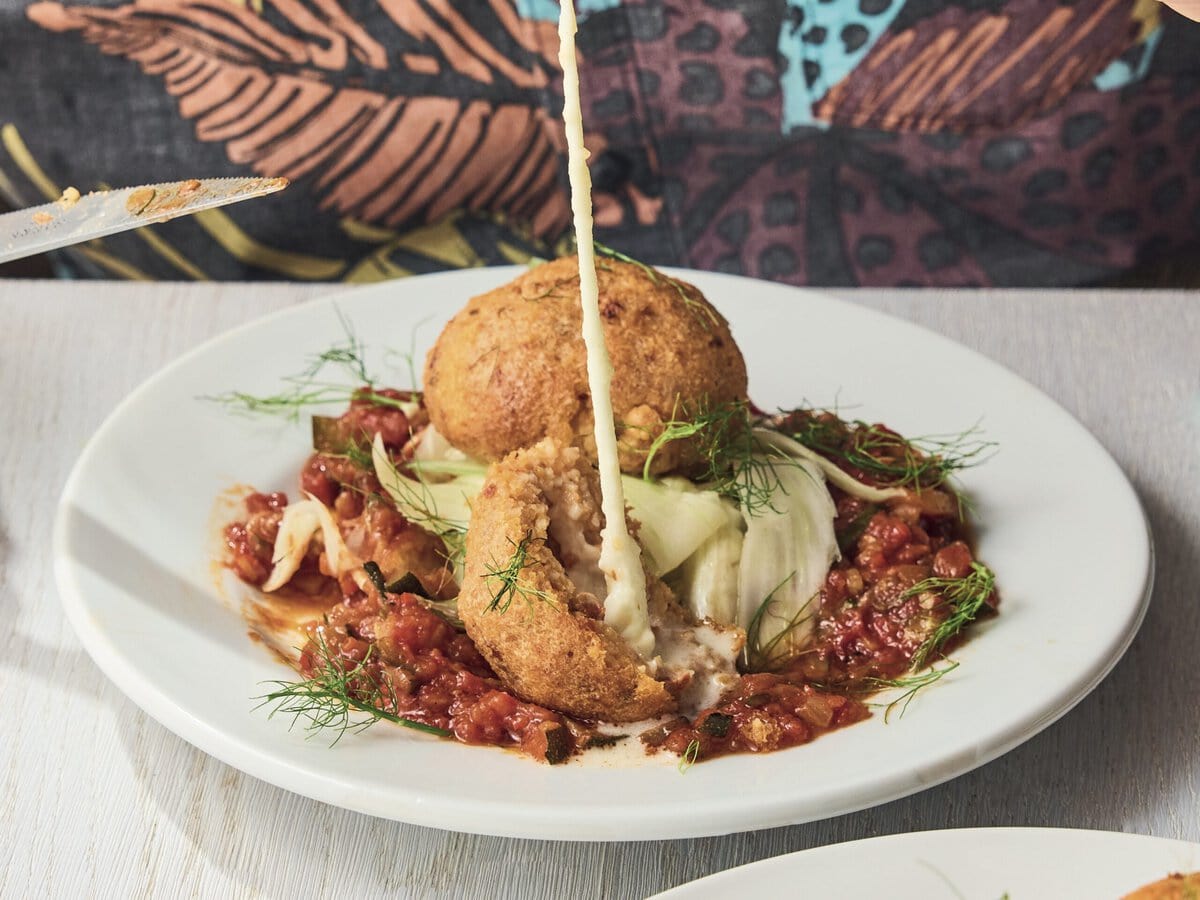 Twee arancini ballen, geserveerd op een tomatensaus en venkel
