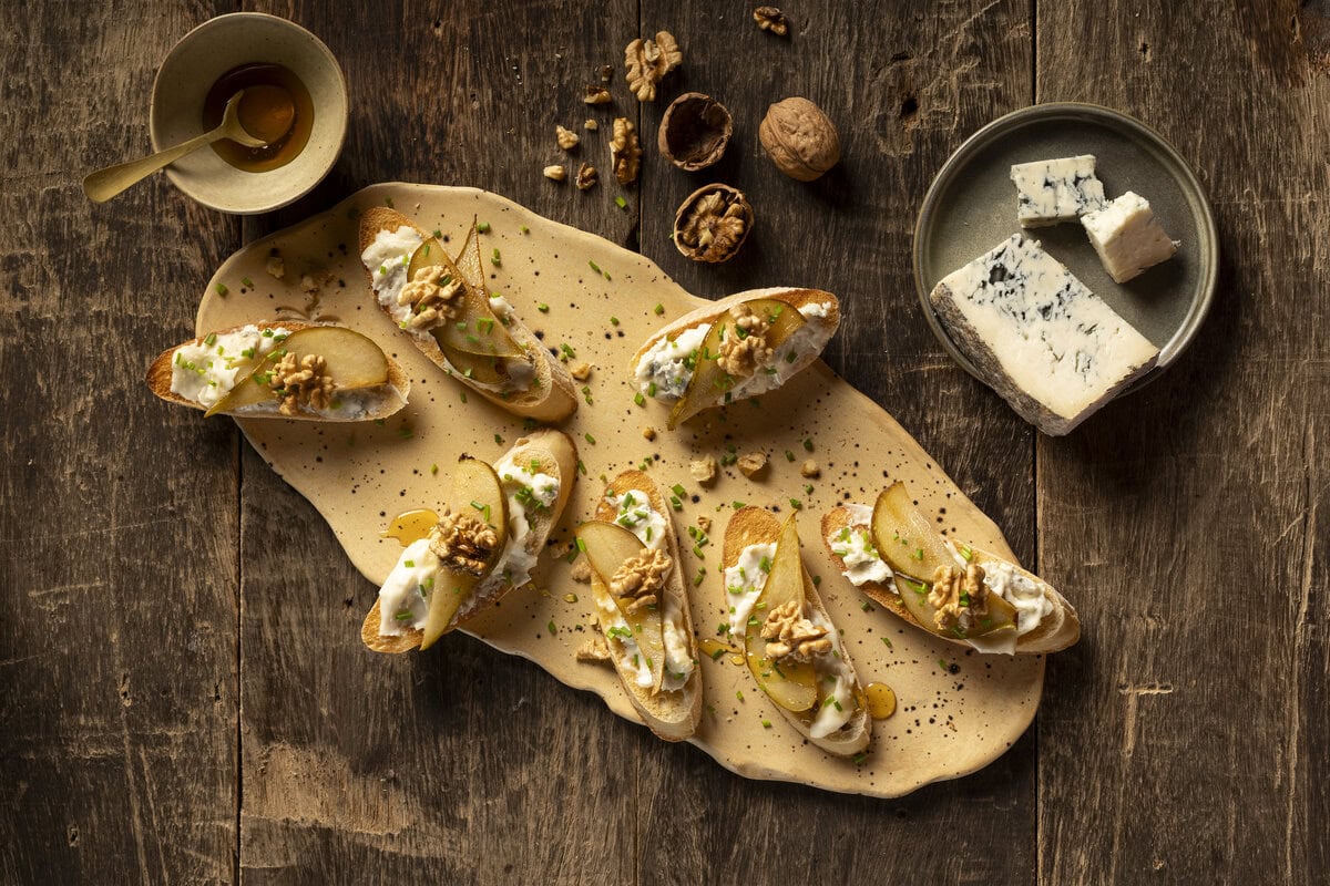 Crosini op een plank met Gorgonzola, peer, honing en walnoot