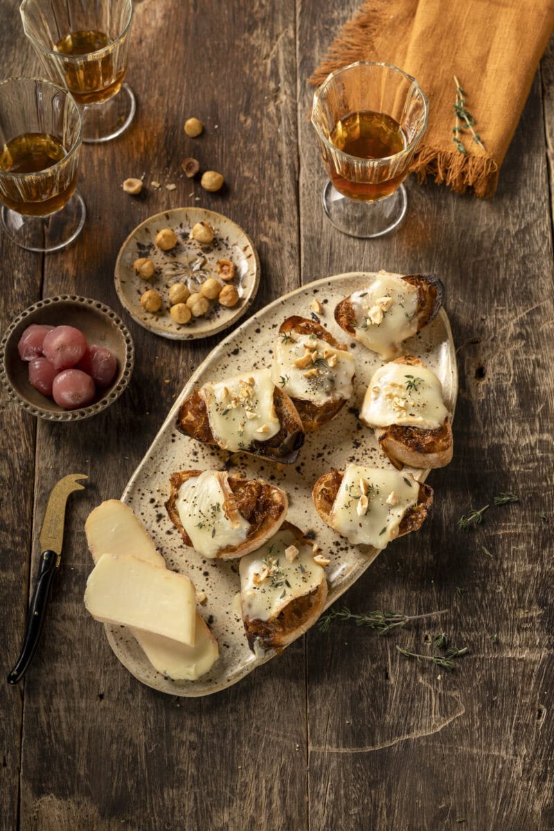 Crostini met gesmolten Taleggio en gekaramelliseerde ui op een plank