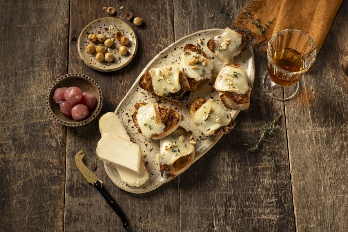 Crostini met gesmolten Taleggio en gekaramelliseerde ui op een plank
