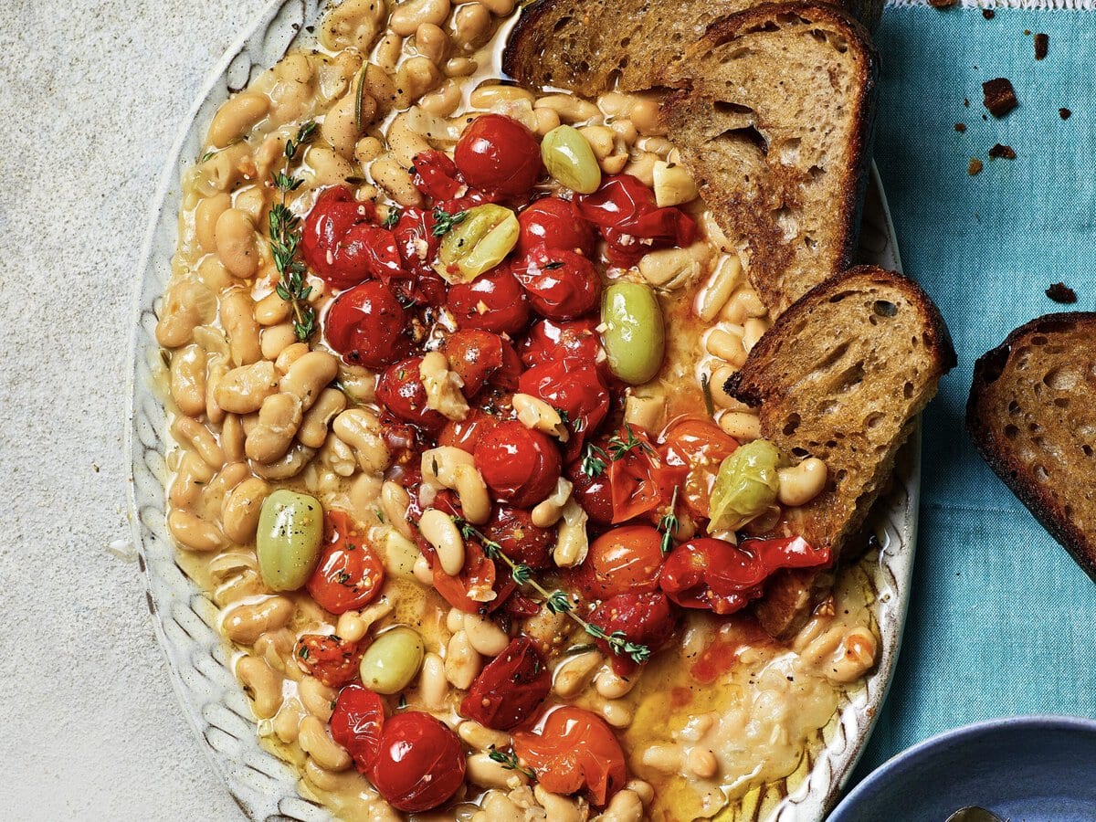 Gekonfijte tomaten met romige bonen en olijfolie, geserveerd met zuurdesembrood