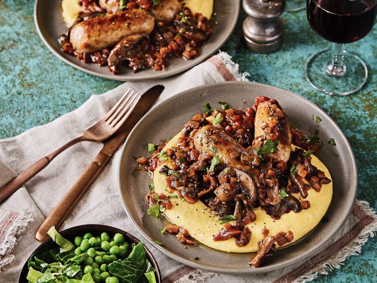 Gestoofde Italiaanse worstjes met champignons, romige polenta en gestoomde groene groenten