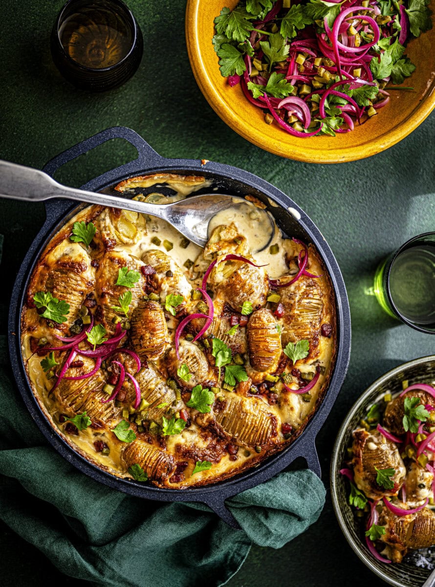 Tartiflette met hasselback aardappelen, peterselie en ingelegde rode ui, geserveerd met picklesalade