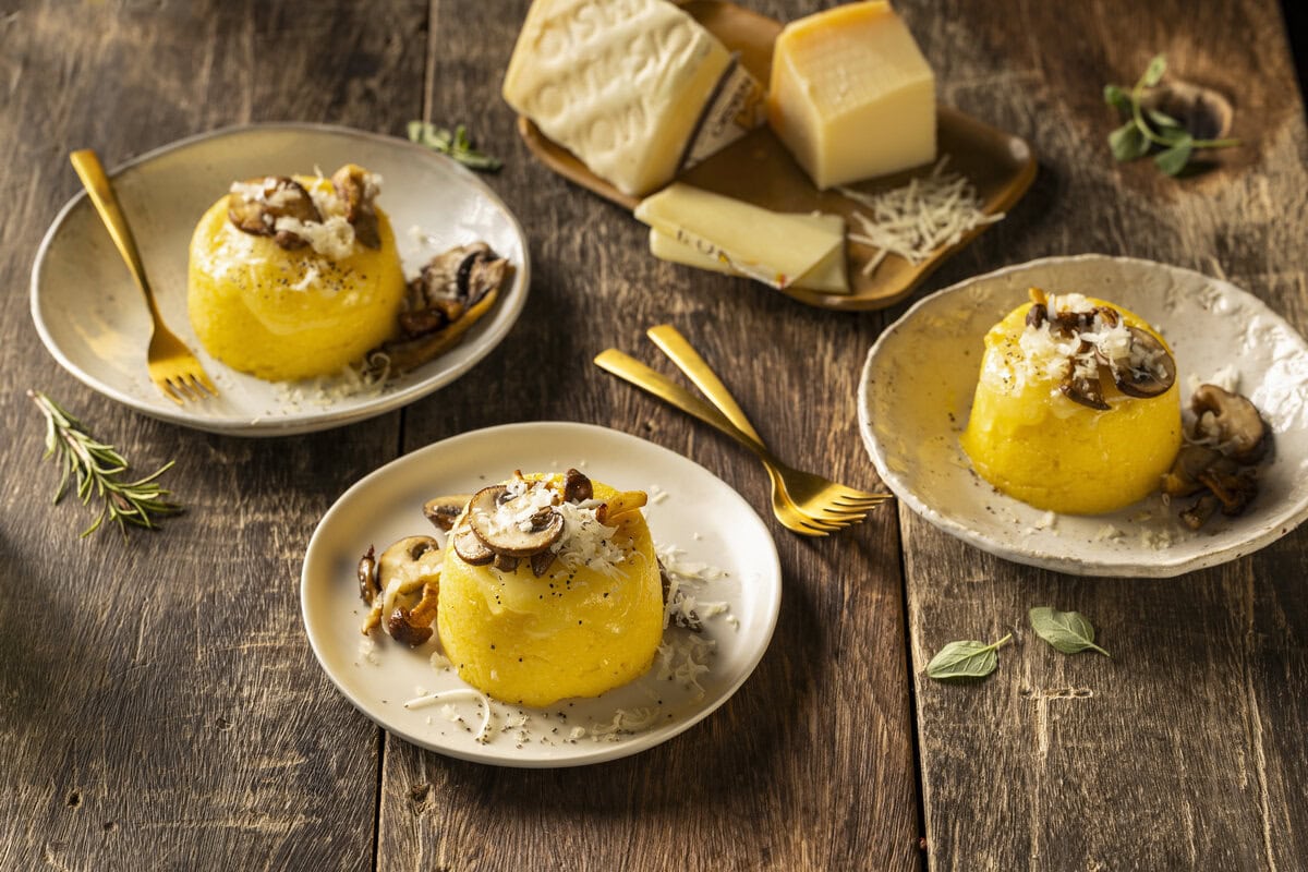 Drie polentataartjes met gesmolten Grana Padano, Montasio en daarop gebakken paddenstoelen
