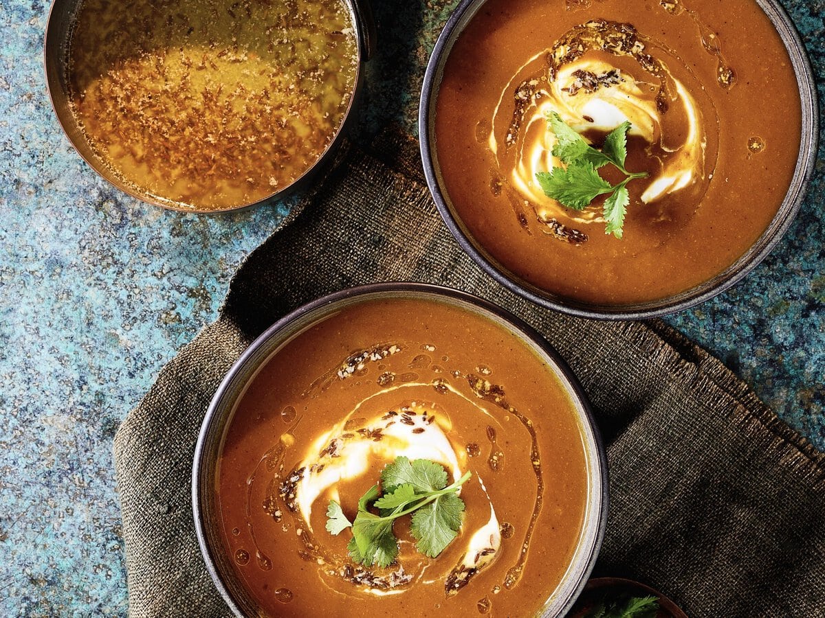 Twee kommen pompoencurrysoep met yoghurt erop