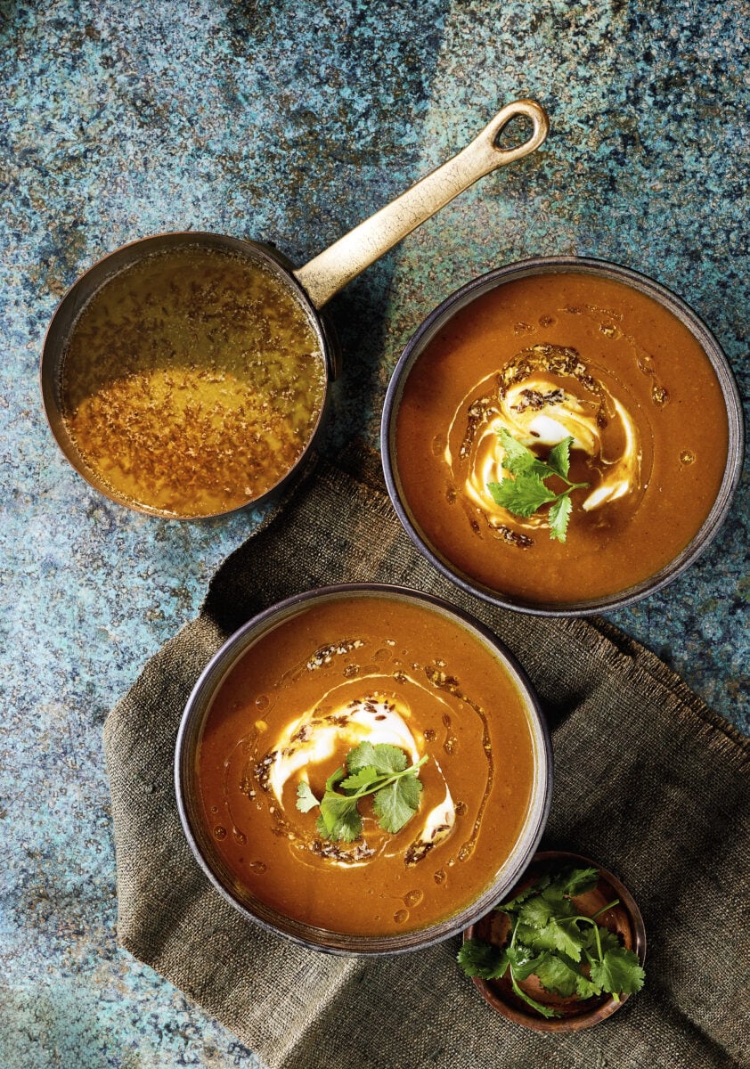 Twee kommen pompoencurrysoep met yoghurt erop