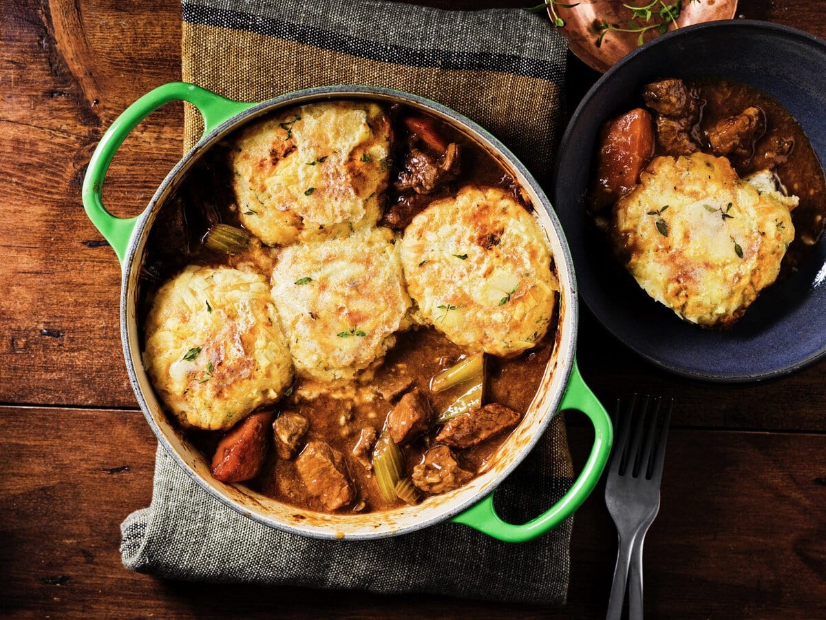 Rundvleesstoof in een pan met daarop cheddar-tijmdumplings