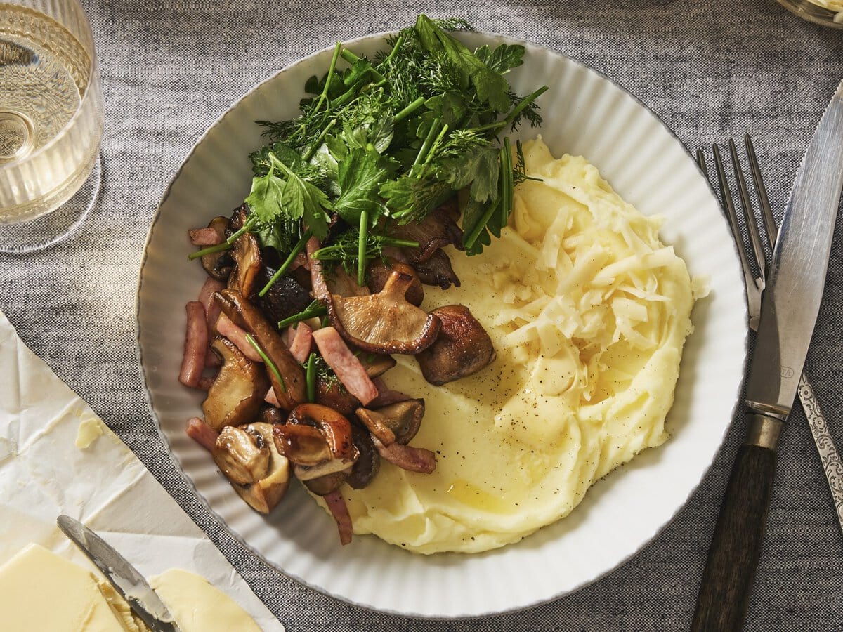 Franse aardappelpuree met paddenstoelen en ham, met daarnaast een groene kruiden salade